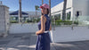 Video of model in navy golf womens dress and pink hat at a resort pool